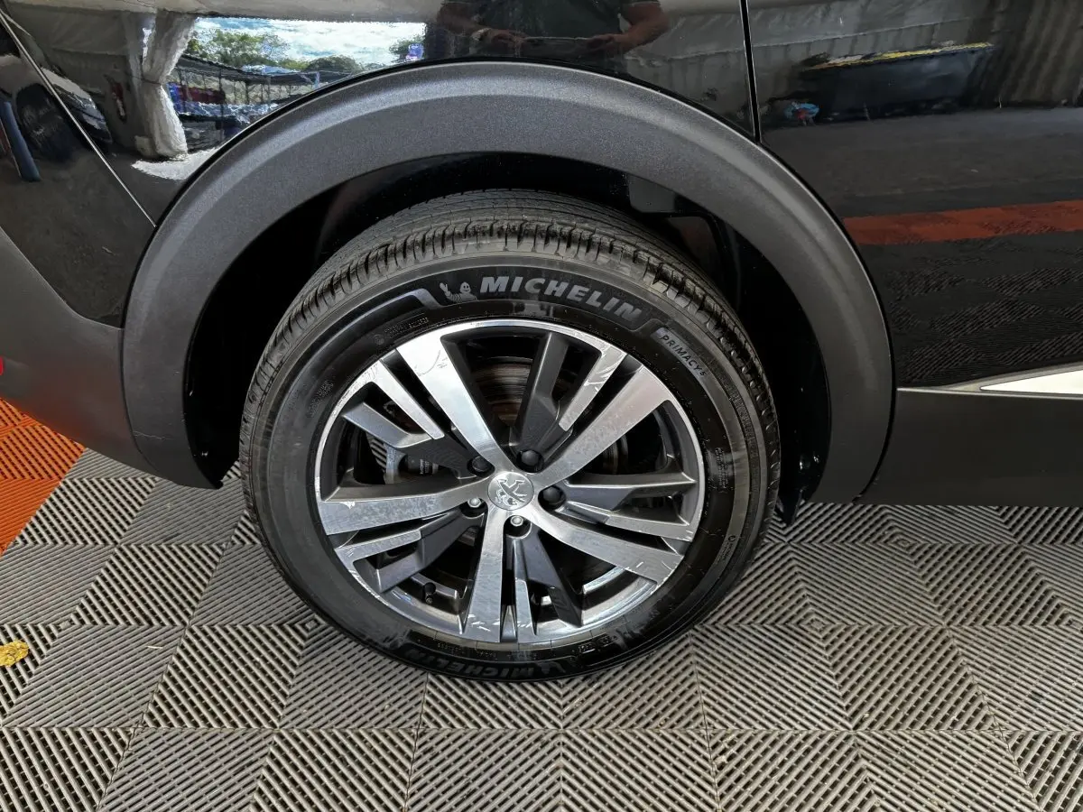 Gros plan sur la roue arrière droite d’un Peugeot 5008 noir, avec jante alliage et pneu Michelin.