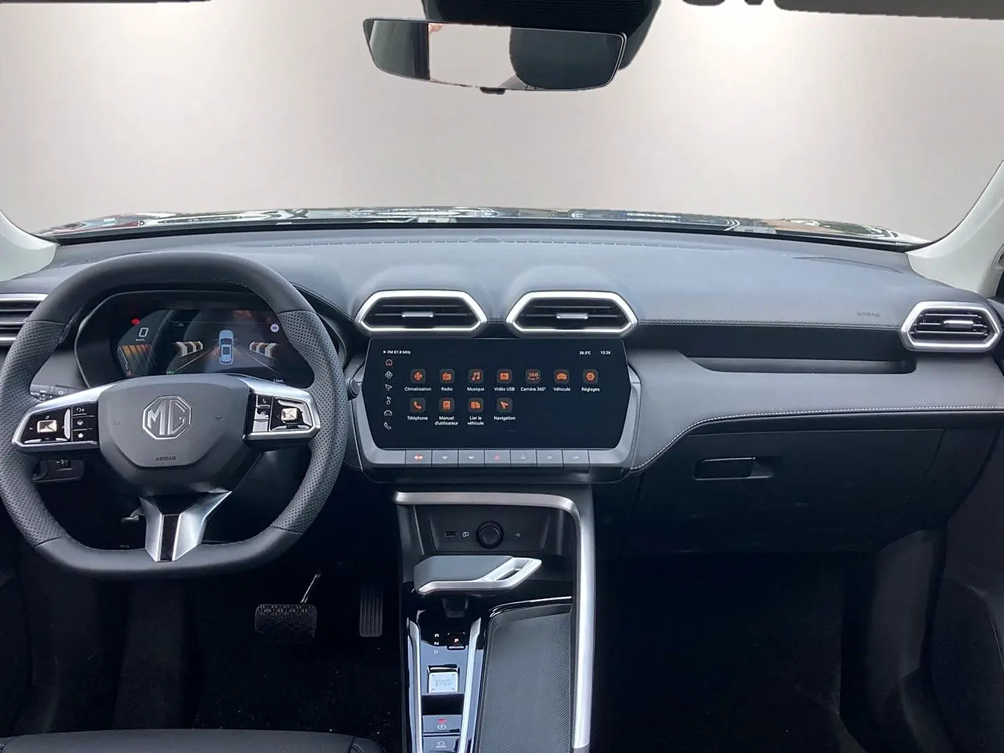 Vue intérieure frontale du tableau de bord noir du MG ZS 1.5 hybrid 197 luxury avec écran tactile central et volant multifonction.