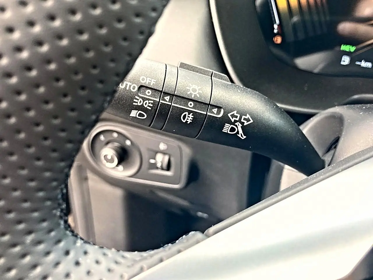 Gros plan sur la commande de phares et clignotants à gauche du volant perforé dans l’habitacle noir du MG ZS 1.5 hybrid 197 luxury.