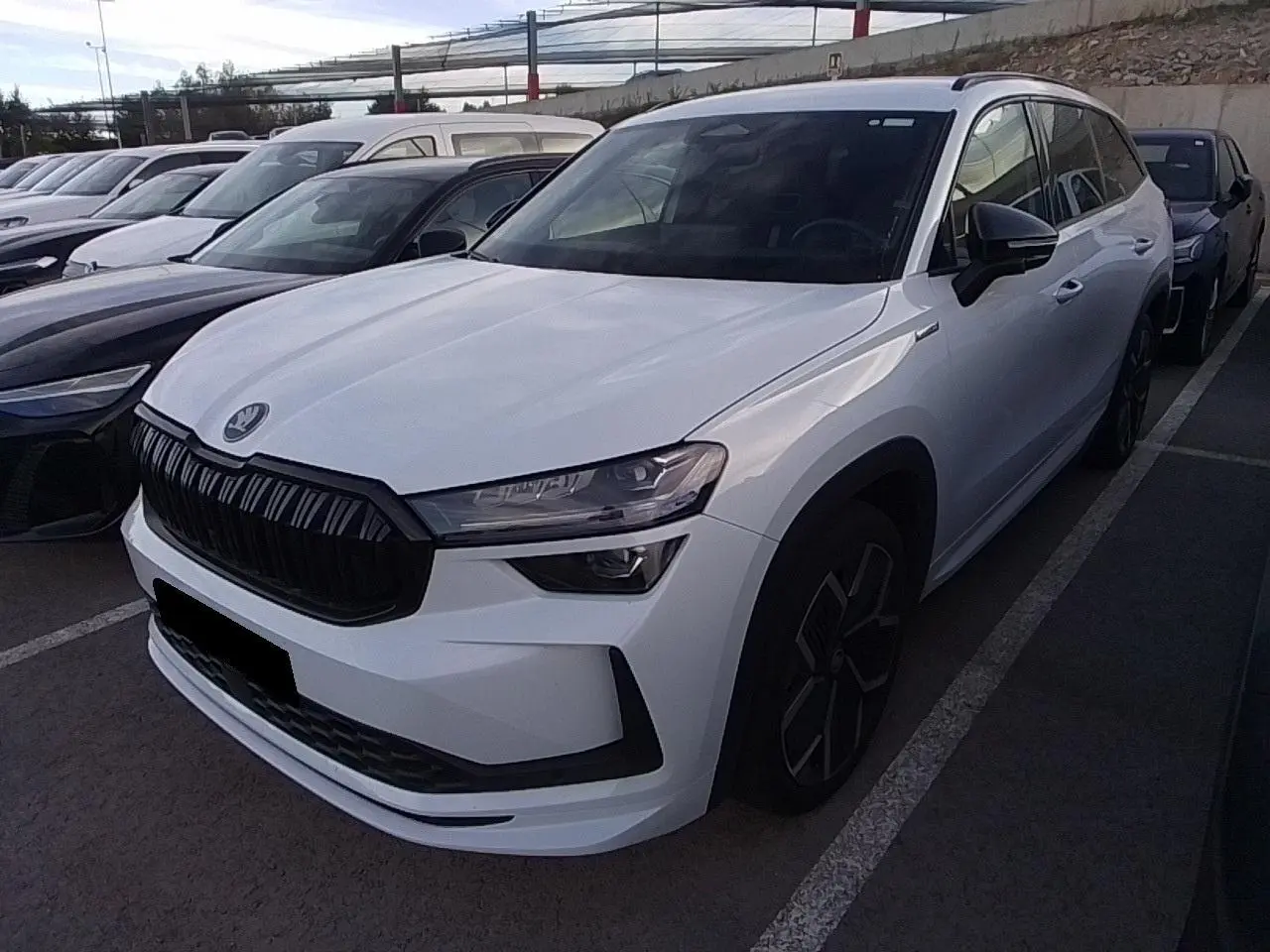 Vue 3/4 avant droite d’un Skoda Kodiaq blanc Glacier avec calandre noire et jantes anthracite 20 pouces.