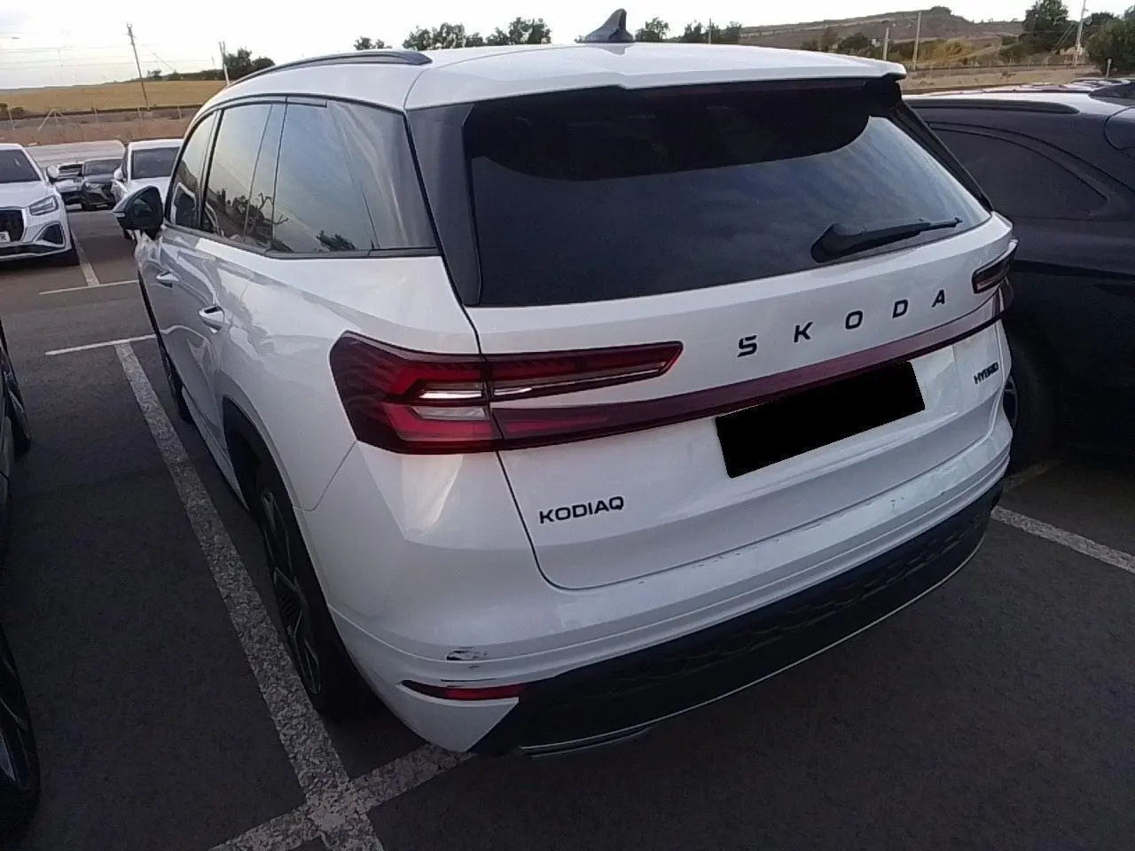 Vue 3/4 arrière gauche d’un Skoda Kodiaq blanc Glacier avec feux arrière LED et vitrage surteinté.