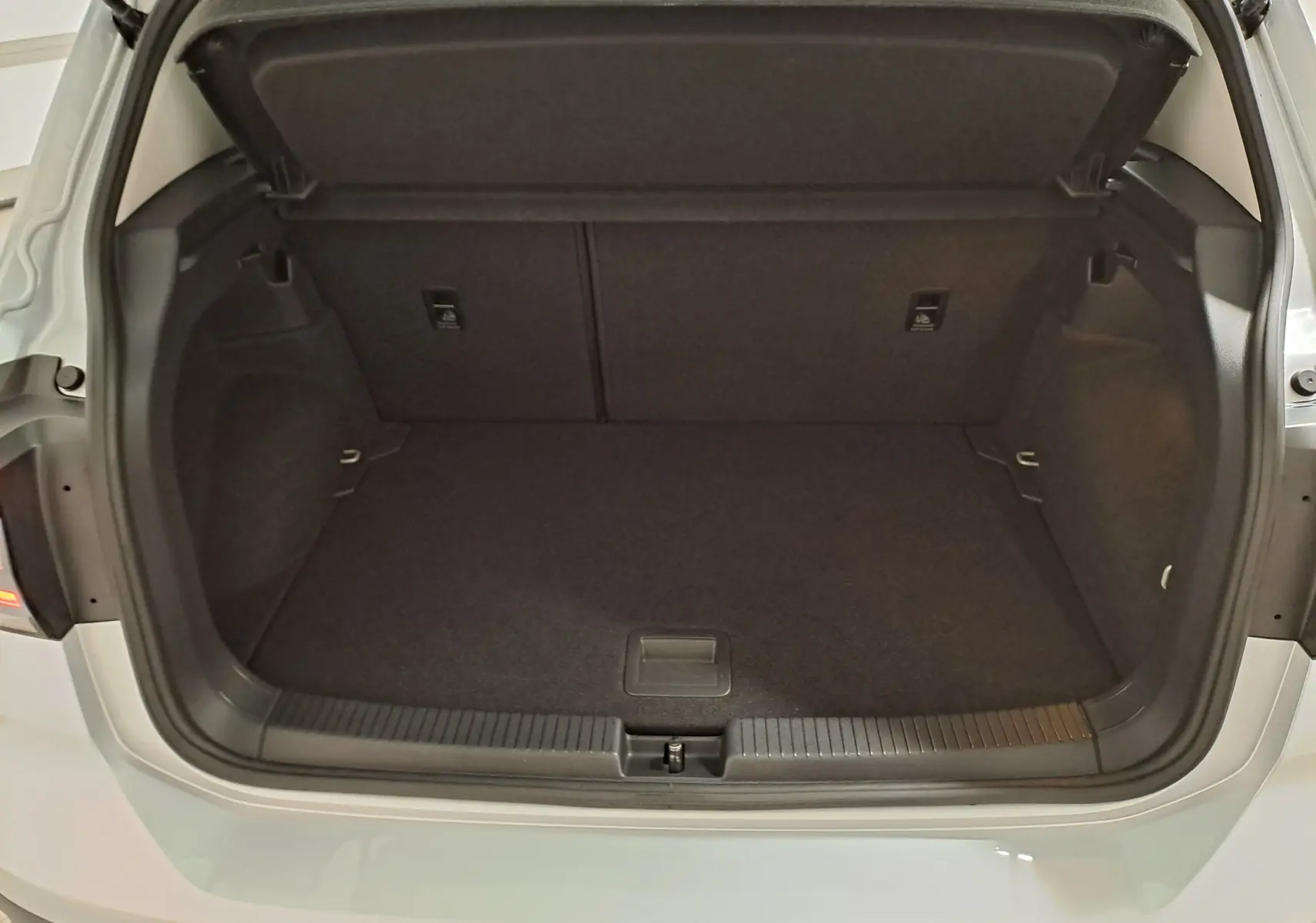 Coffre ouvert vu de face d'un Volkswagen T-Cross 2022 argenté, montrant un espace de chargement propre et vide.