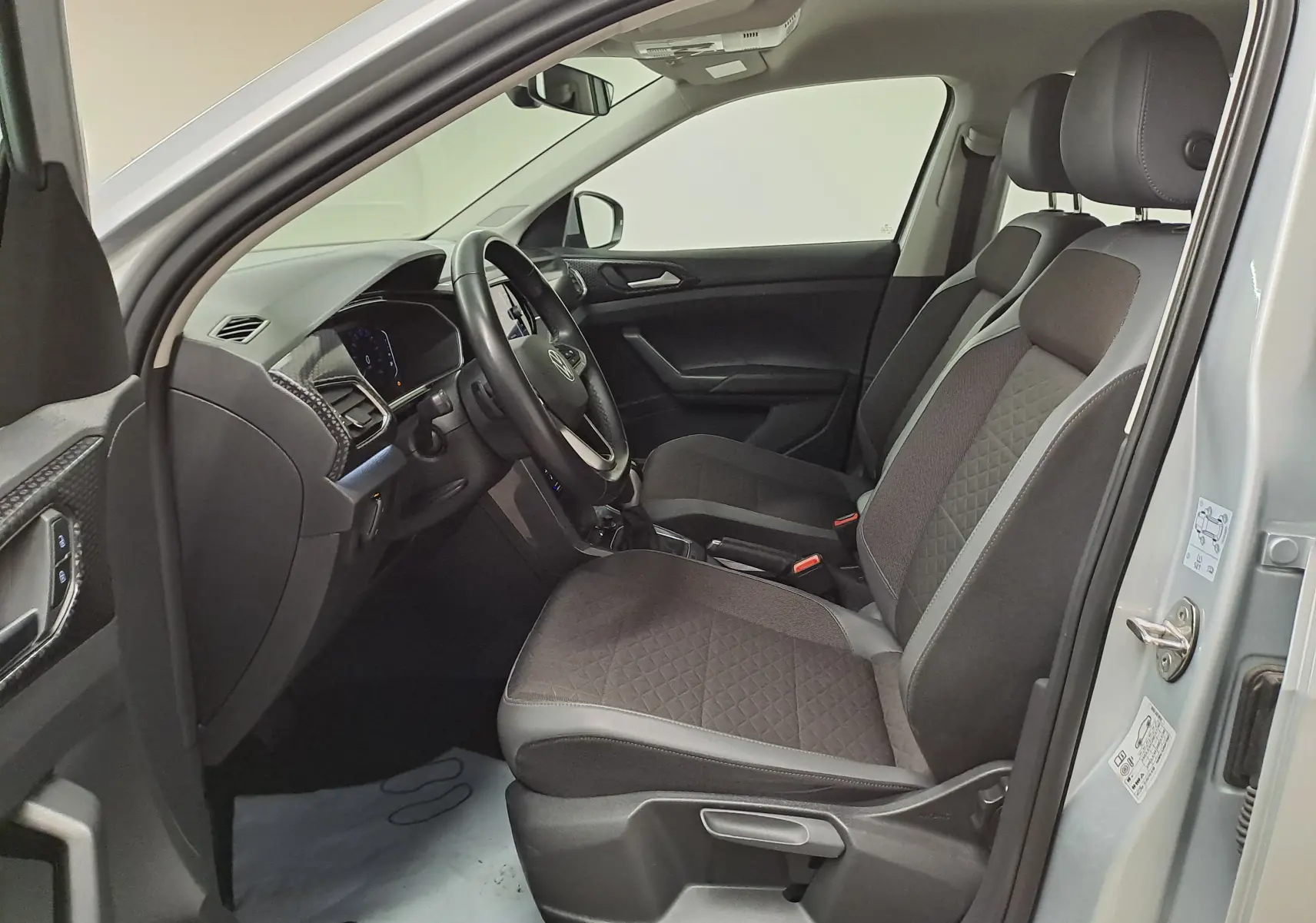 Vue intérieure côté conducteur du Volkswagen T-Cross 2022 en Reflet d'argent, sièges noirs et tableau de bord moderne.