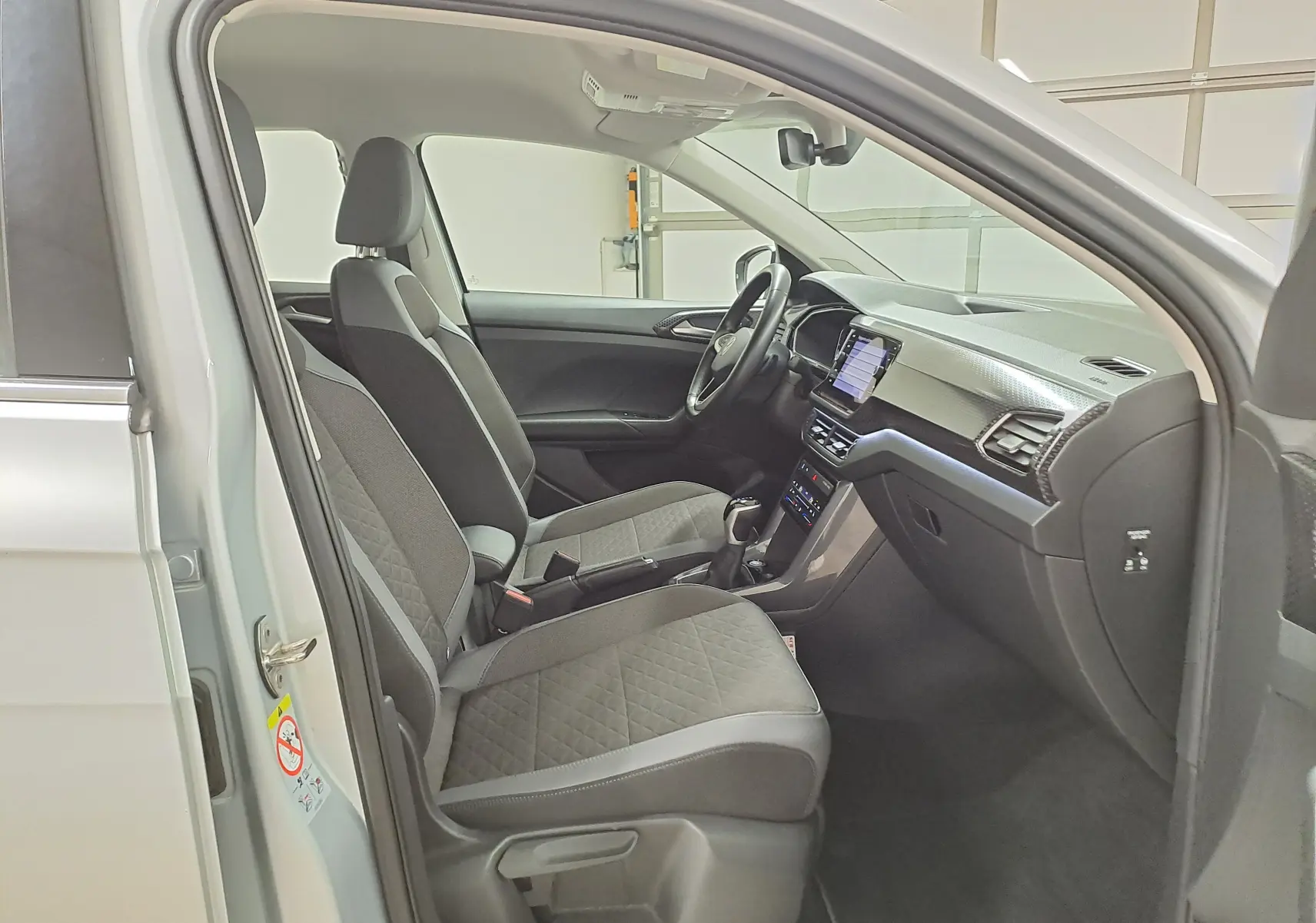 Vue intérieure côté conducteur du Volkswagen T-Cross 2022 argent, montrant sièges et tableau de bord moderne.