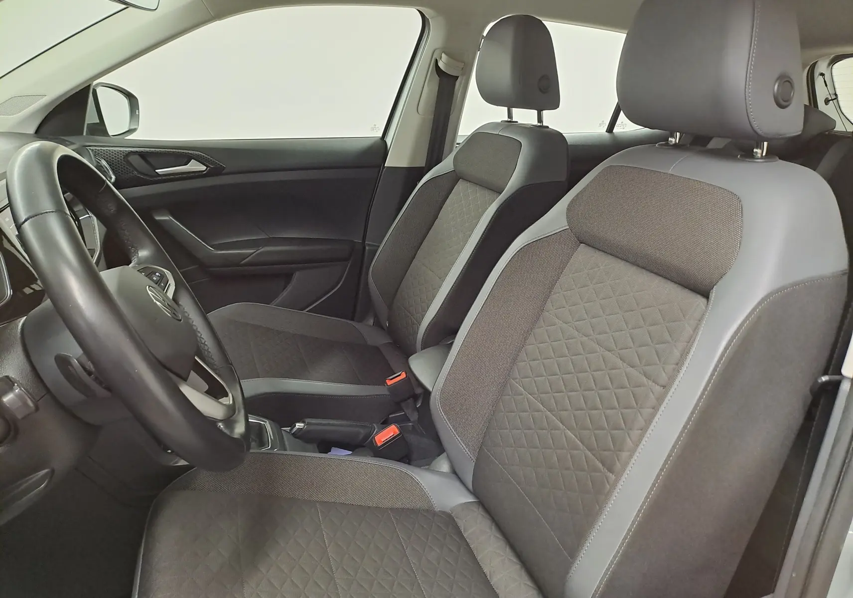 Vue intérieure côté gauche du Volkswagen T-Cross 2022, sièges avant gris avec surpiqûres en losange et volant noir.