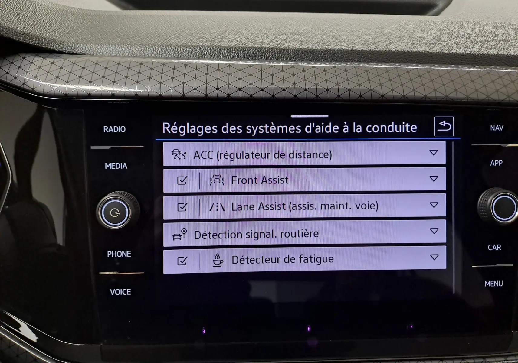Écran tactile central du Volkswagen T-Cross 2022 montrant les réglages des aides à la conduite avec interface noire brillante.