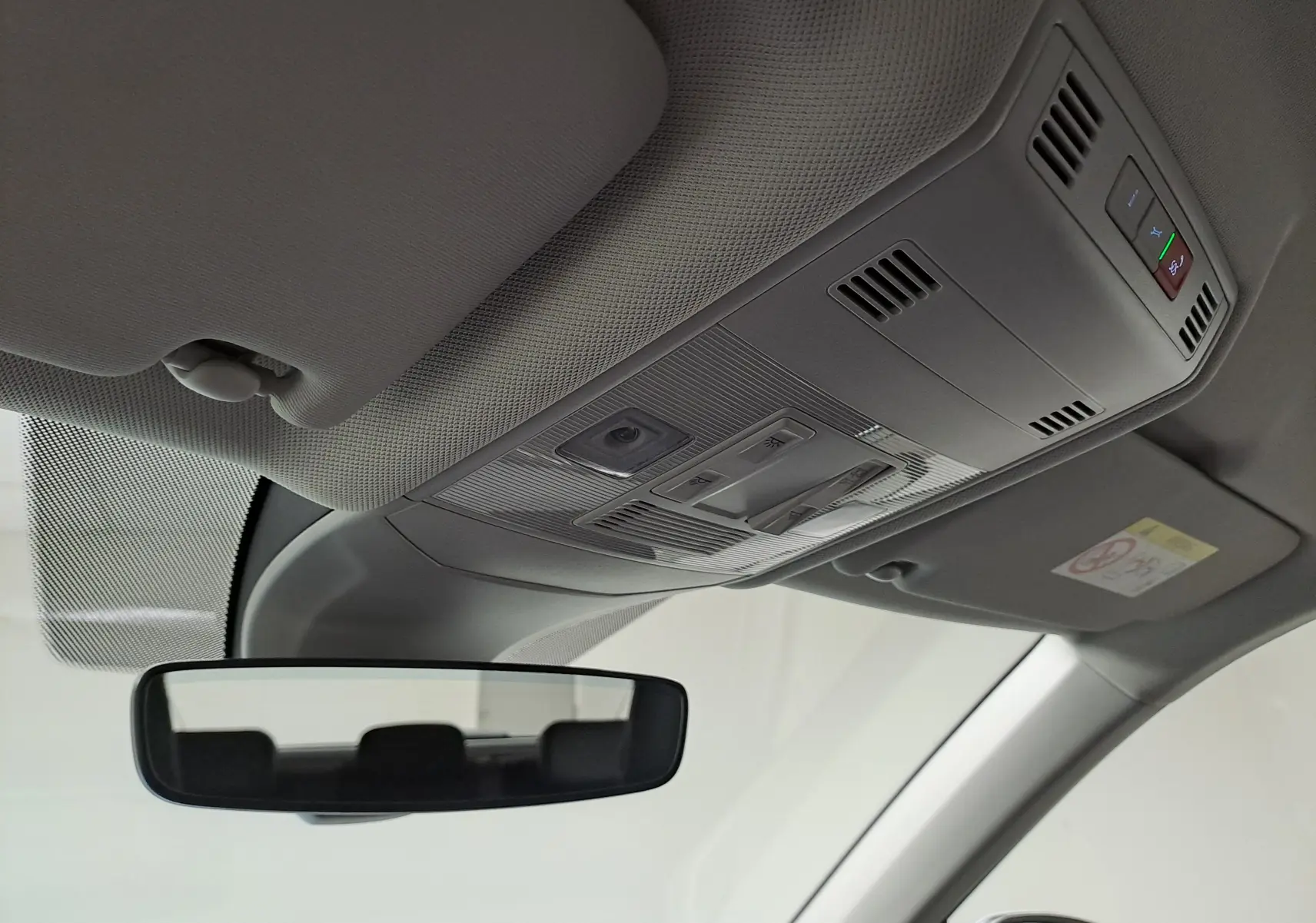 Vue intérieure du plafond avant du Volkswagen T-Cross 2022, montrant les commandes d’éclairage et le rétroviseur central.
