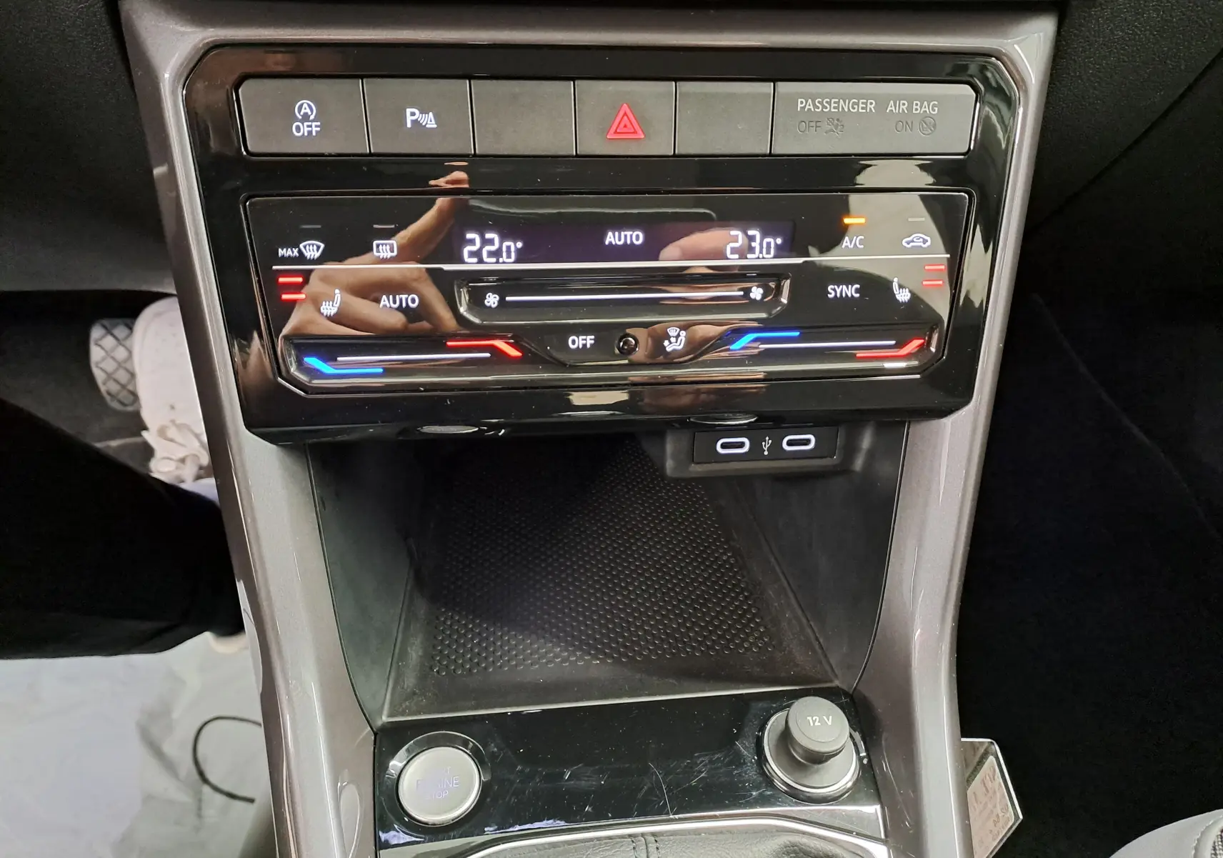 Vue rapprochée du tableau de bord central du Volkswagen T-Cross 2022, avec commandes climatisation digitale et ports USB visibles.