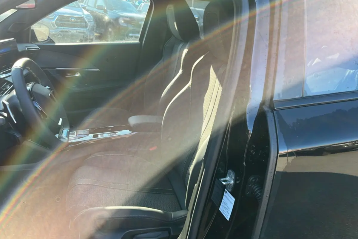 Vue intérieure côté conducteur du Peugeot 2008 noir perla nera, mettant en valeur les sièges et le volant cuir multifonctions.