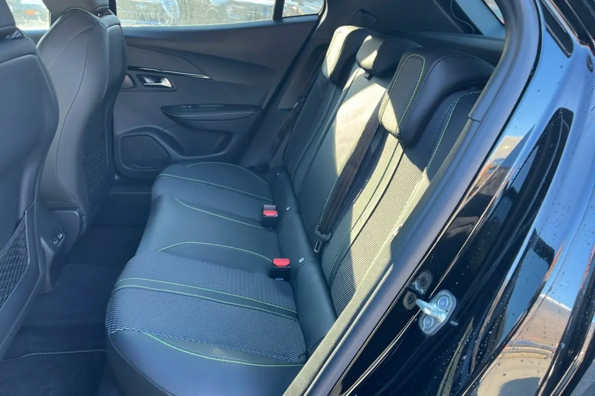 Vue intérieure côté gauche sur la banquette arrière en cuir tissu noir avec surpiqûres vertes du Peugeot 2008 Hybrid 145 GT Vision 2025.