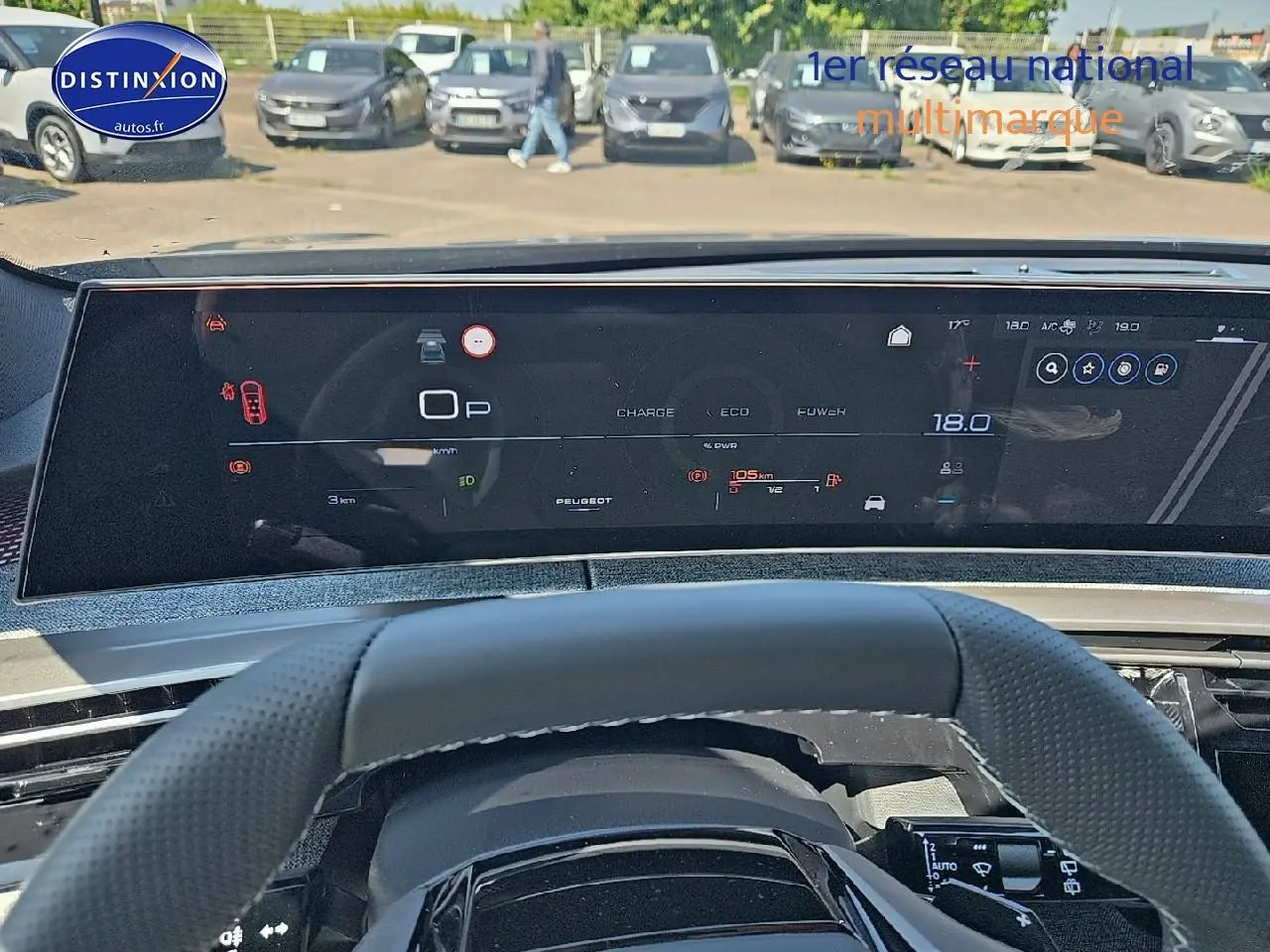 Vue intérieure du tableau de bord numérique et volant cuir perforé d'une Peugeot 5008 gris titane, version Hybrid 145 GT.