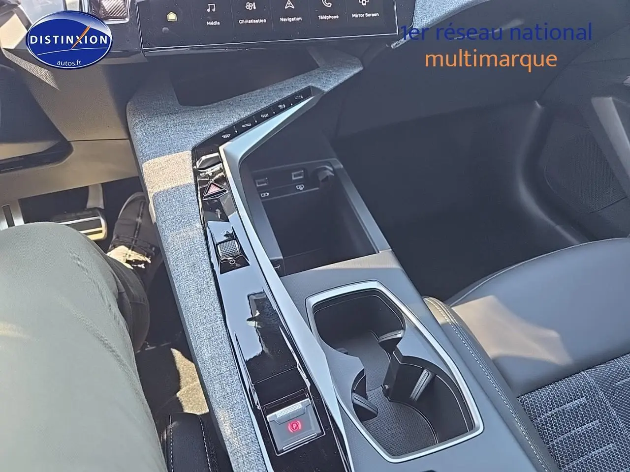 Vue intérieure centrée sur la console centrale et accoudoir du Peugeot 5008 Hybrid 145 gris titane, avec sellerie cuir et tissu.