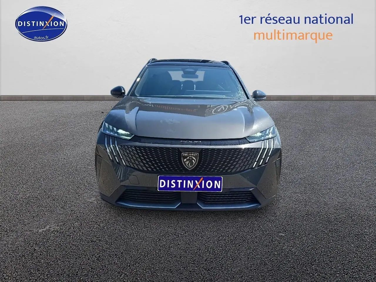 Vue de face du Peugeot 5008 Hybrid 145 GT gris titane avec calandre noire et phares LED allumés.