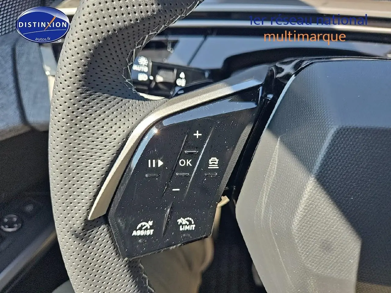 Gros plan sur le volant cuir perforé côté gauche du Peugeot 5008 gris titane avec commandes multifonctions.