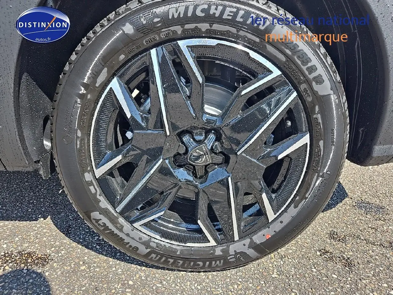Gros plan sur la jante alu noire et argentée d'un Peugeot 5008 gris titane, avec pneu Michelin visible.