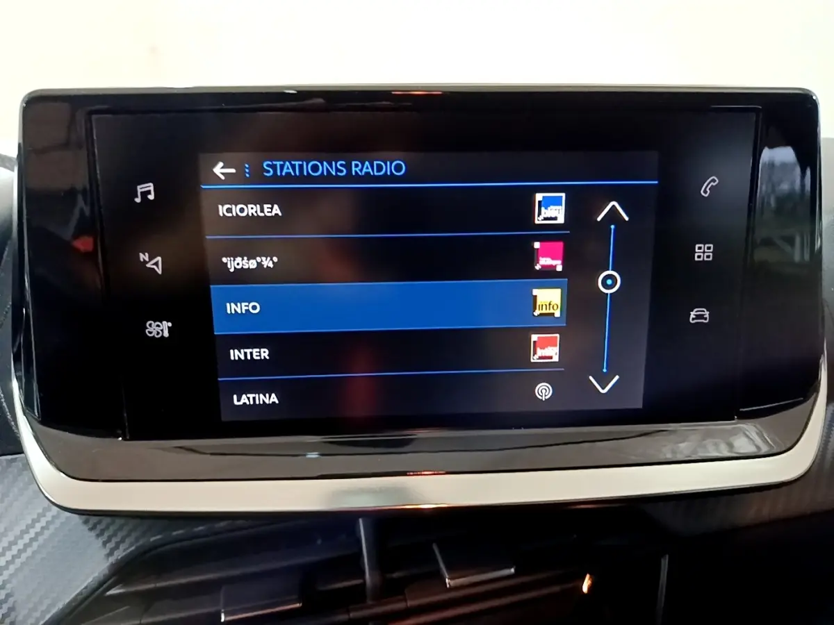 Écran tactile central affichant les stations radio dans l’habitacle d’une Peugeot 208 blanche, vue de face.