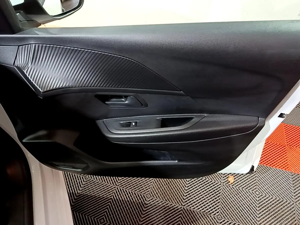 Vue intérieure côté gauche de la porte avant blanche du Peugeot 208 1.5 BlueHDi avec insert noir texturé.