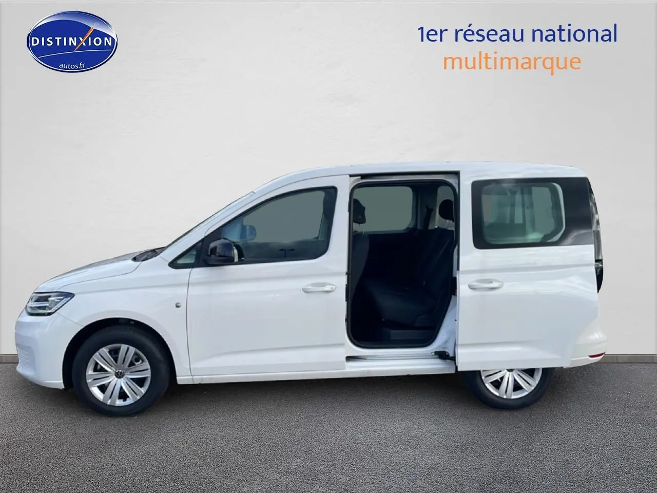 Vue latérale droite d’un Volkswagen Caddy blanc 2025 avec porte coulissante arrière ouverte, intérieur sombre visible.