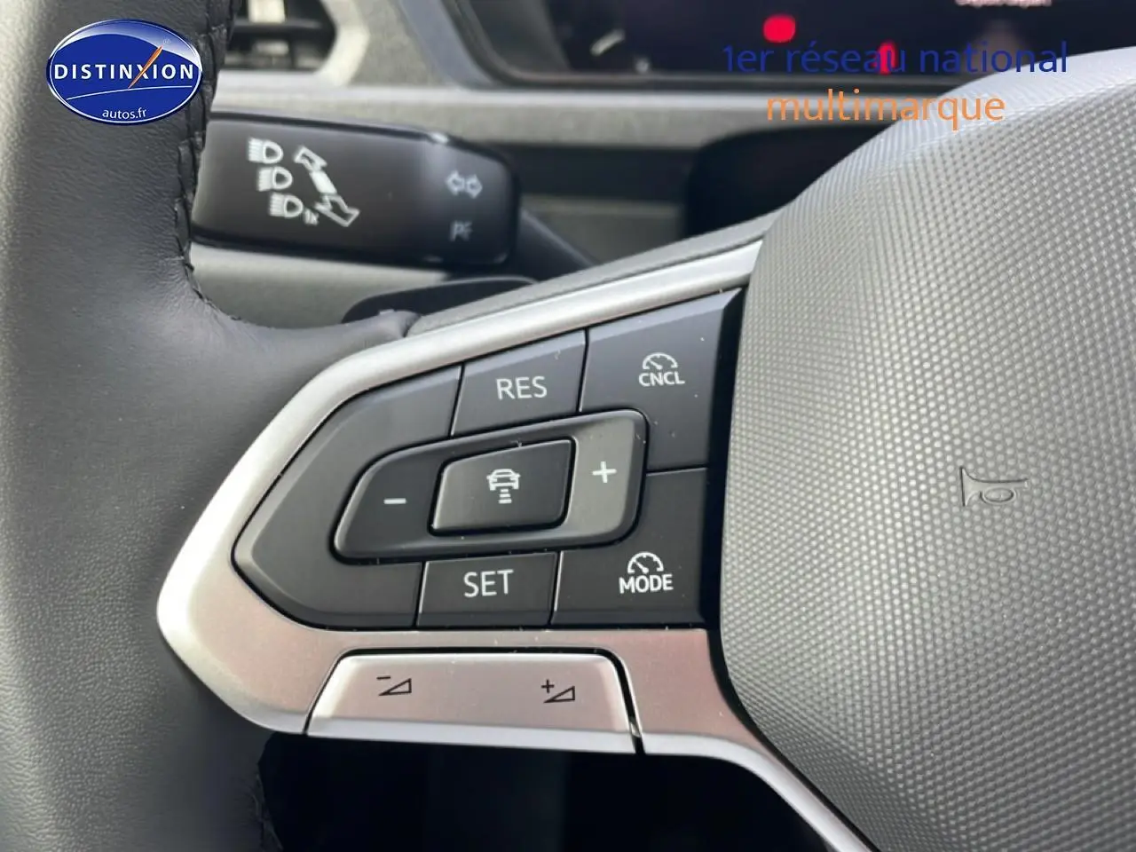 Gros plan sur les commandes du volant cuir multifonction du Volkswagen Caddy blanc, version 2025, côté gauche.