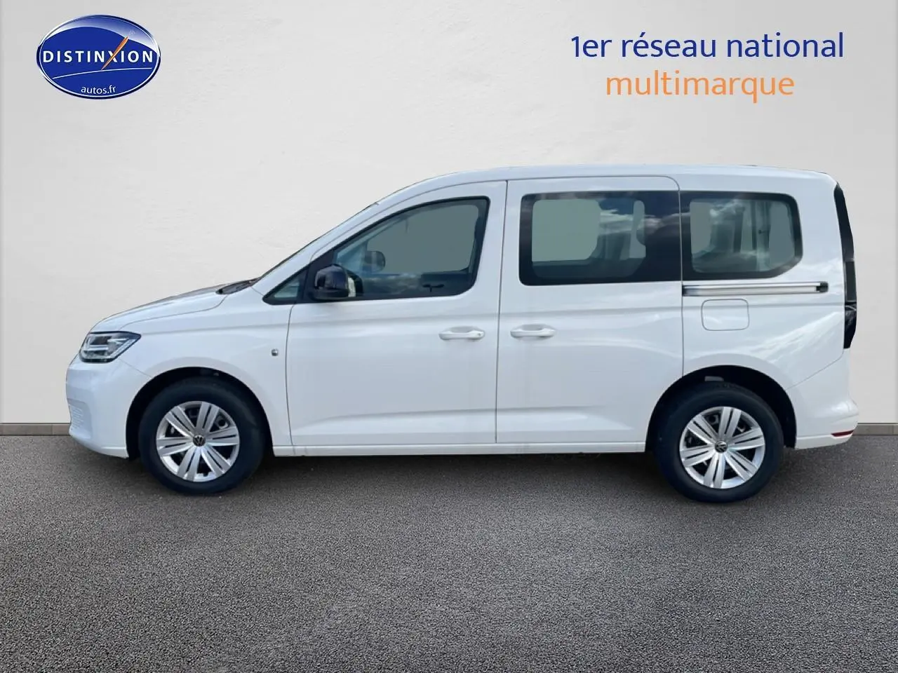 Profil droit d'un Volkswagen Caddy blanc 2025, avec barres de toit et jantes alliage visibles.