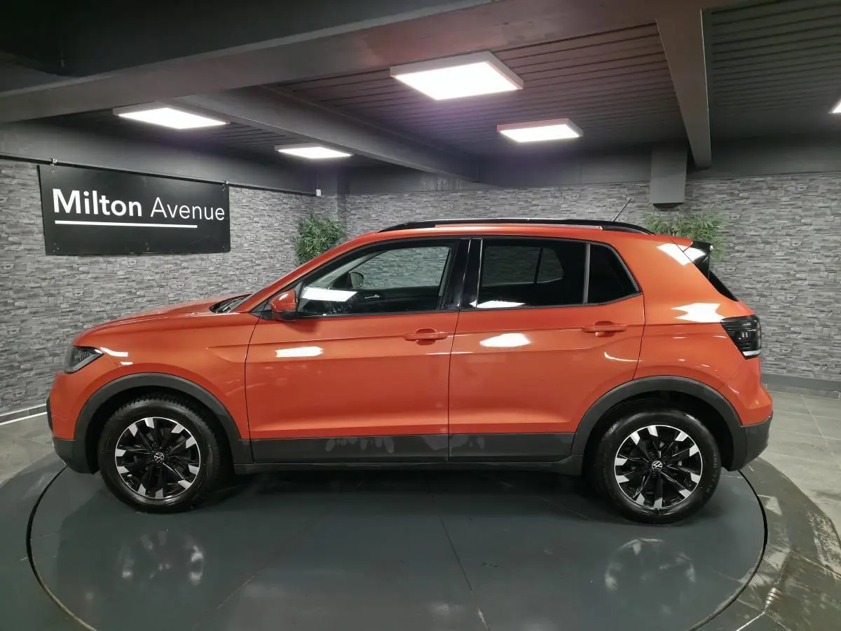 Volkswagen T-Cross orange Energy vue de profil côté gauche, jantes alliage noires et toit noir contrasté.