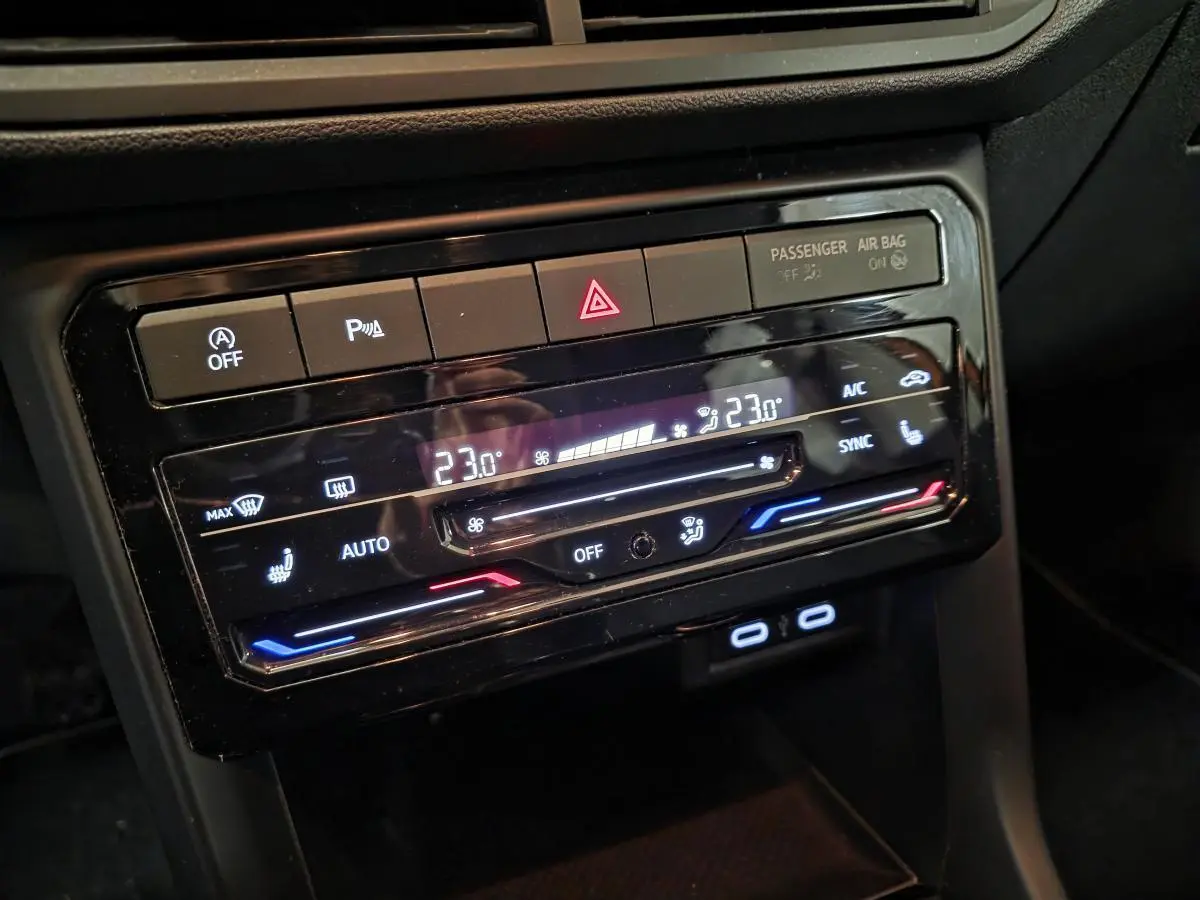 Gros plan sur la console centrale noire du Volkswagen T-Cross 1.0 TSI Active avec commandes de climatisation digitales.