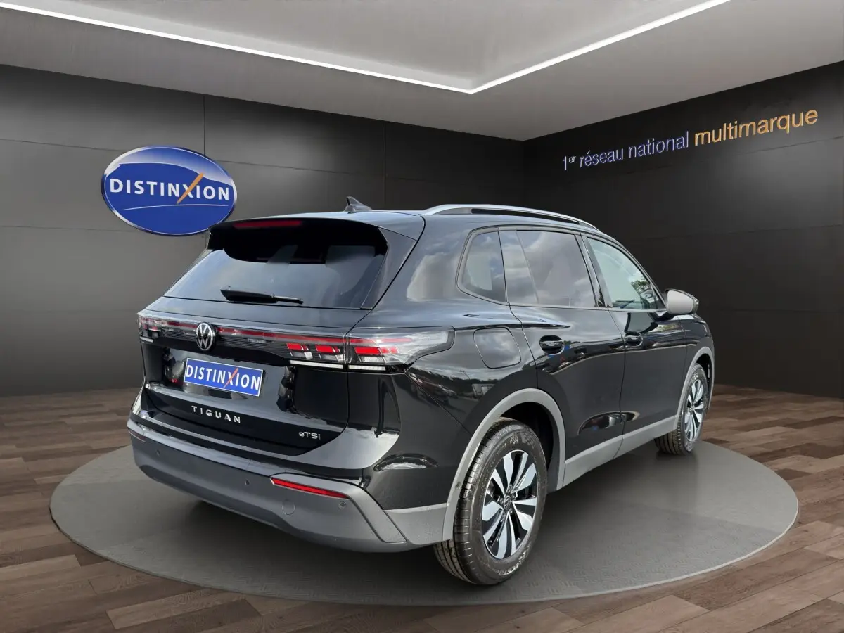 Vue 3/4 arrière droite du Volkswagen Tiguan noir avec feux arrière LED et jantes alliage en showroom.