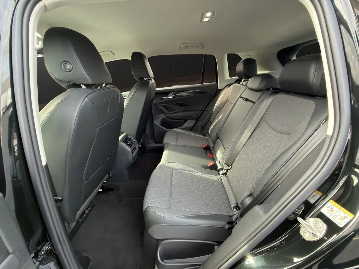 Vue intérieure arrière côté droit du Volkswagen Tiguan noir 2026, sièges tissu et cuir gris avec accoudoirs centraux.