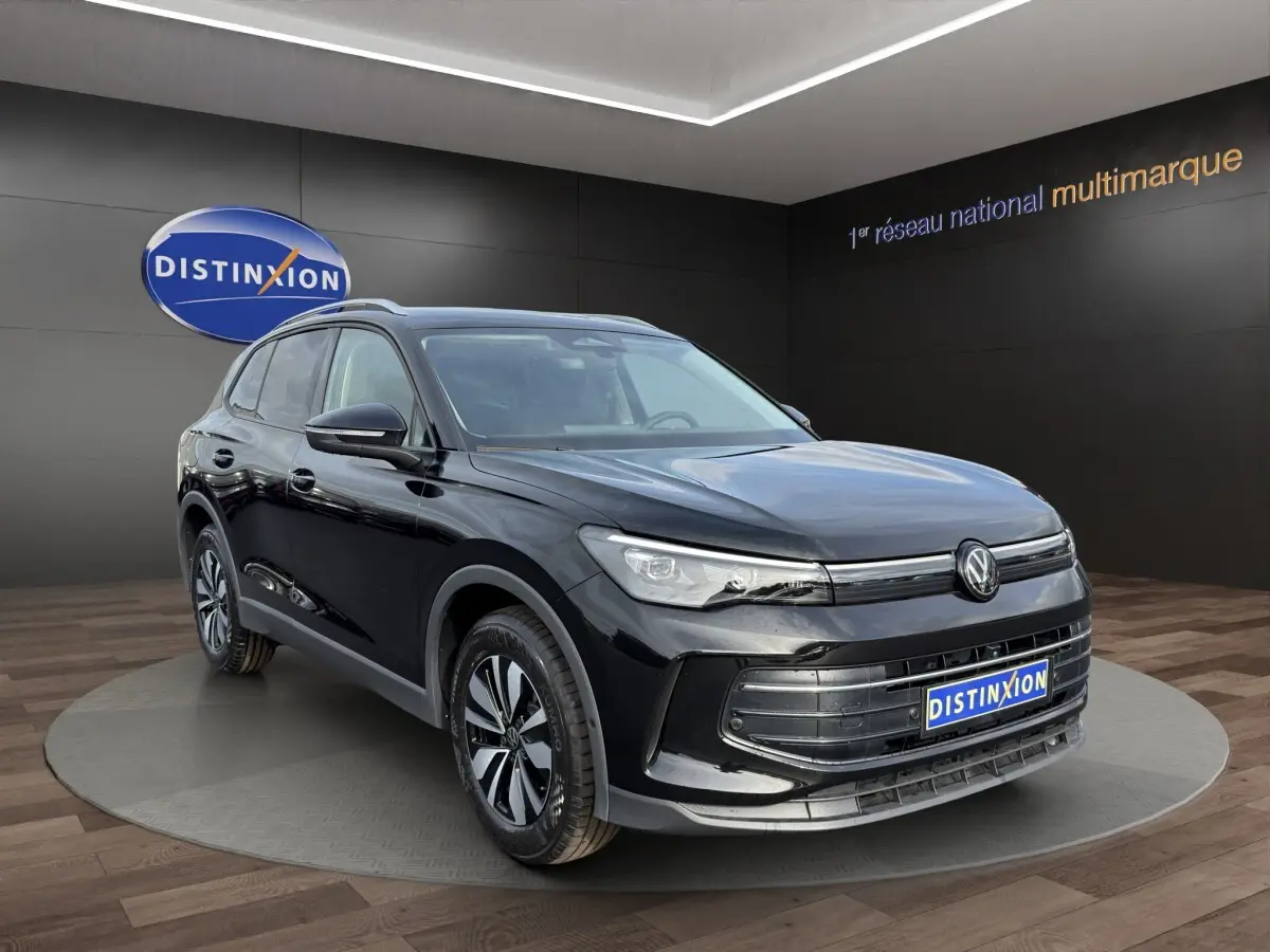 Volkswagen Tiguan noir en 3/4 avant droit, avec calandre chromée et jantes alliage distinctives.