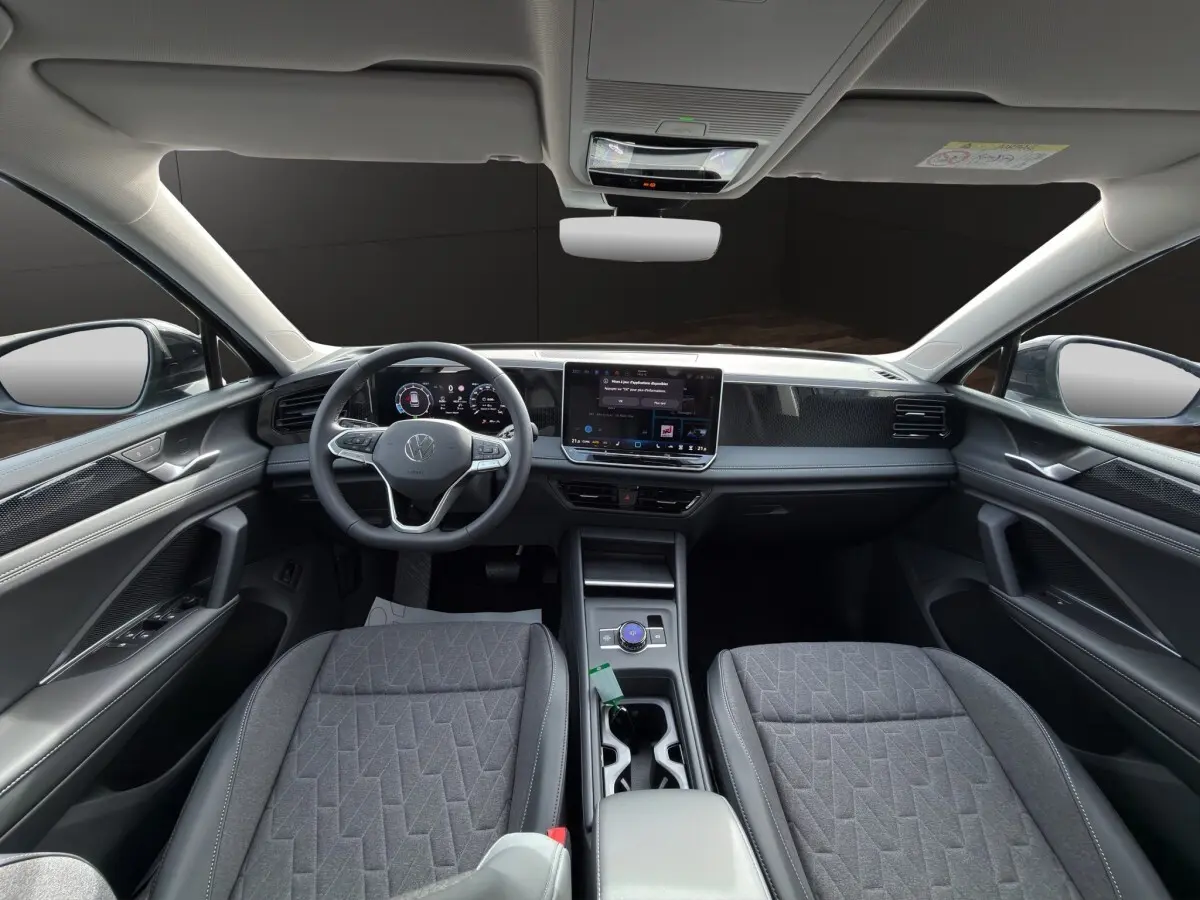 Vue intérieure avant du Volkswagen Tiguan 2026, tableau de bord moderne avec écran tactile central et sièges gris.