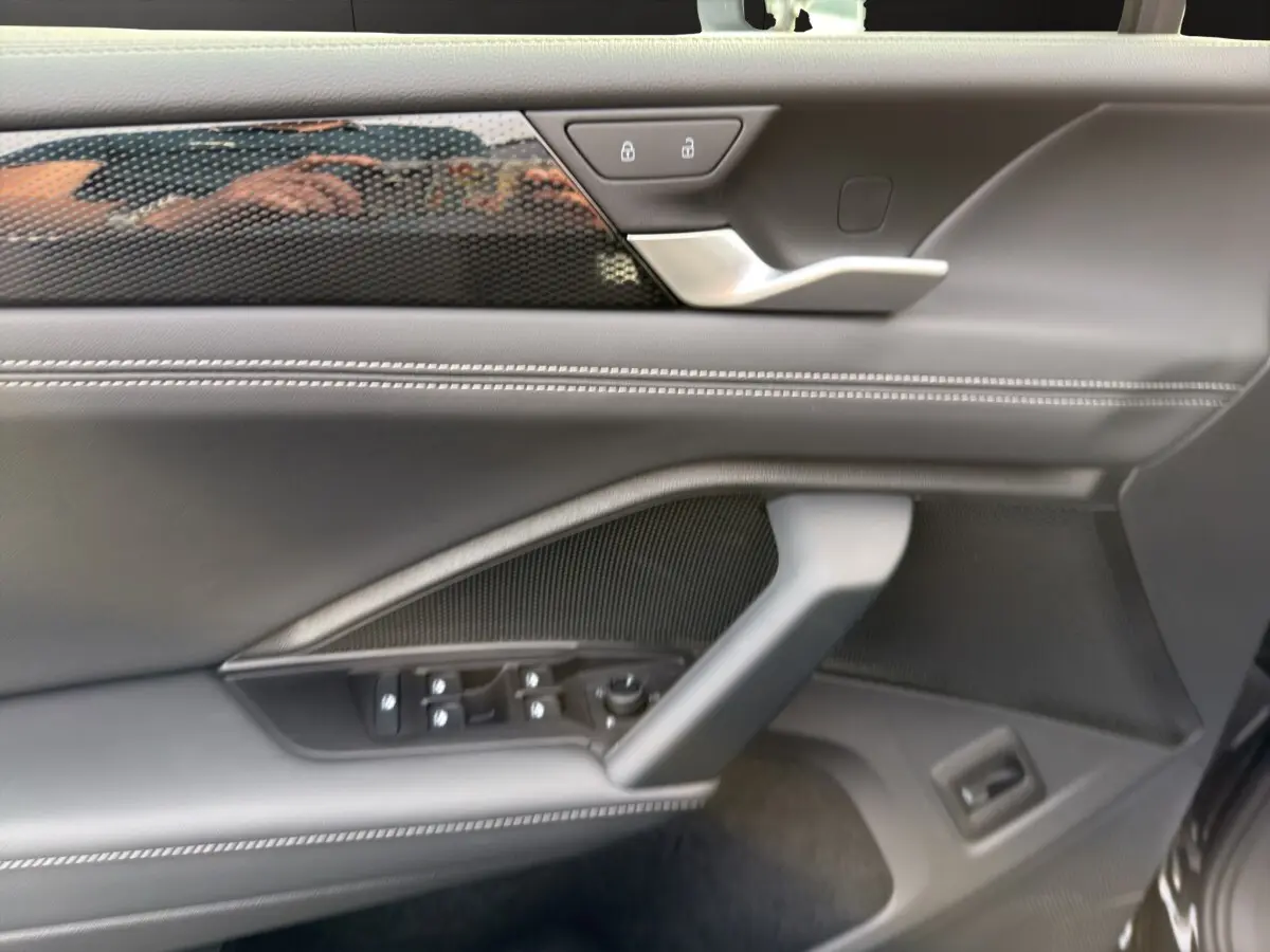 Détail de la porte intérieure côté conducteur du Volkswagen Tiguan noir, avec commandes électriques et finition cuir noire.