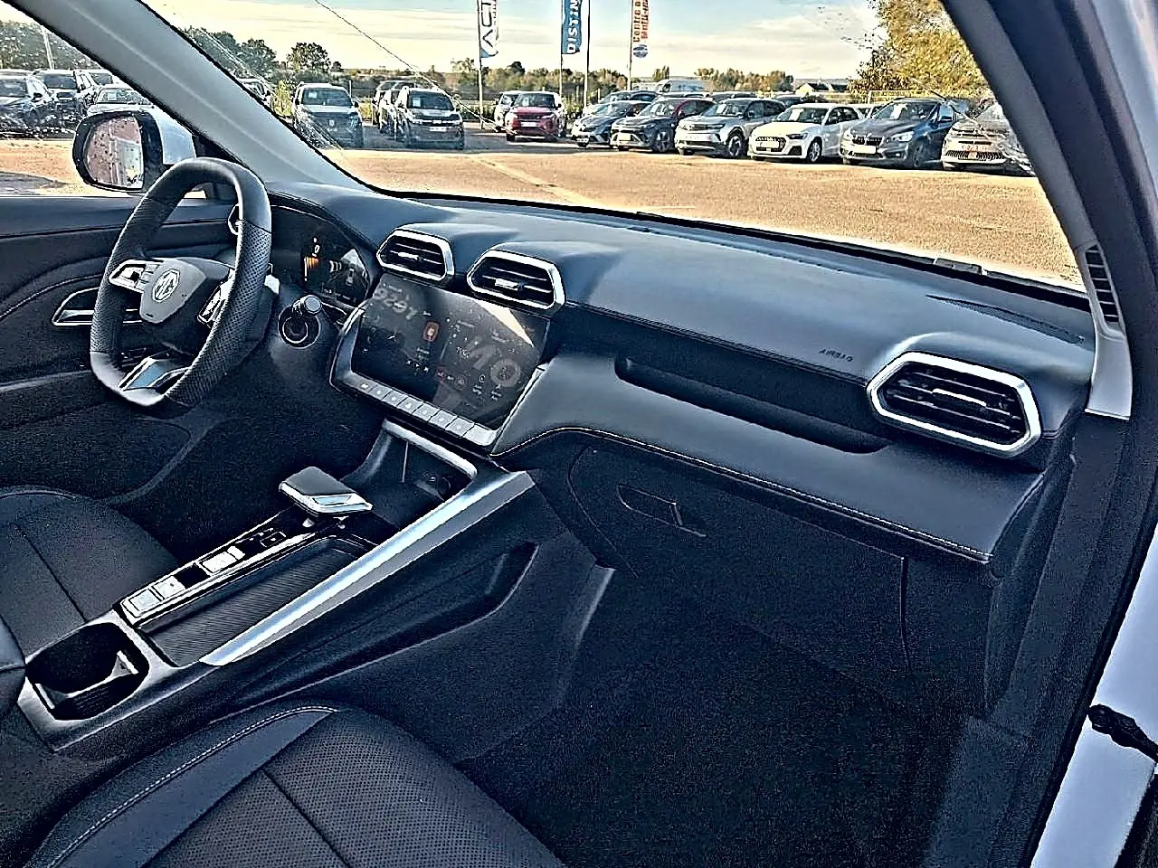 Intérieur noir du MG Motor ZS 1.5 hybrid 197 luxury vu côté passager, avec tableau de bord moderne et écran tactile.