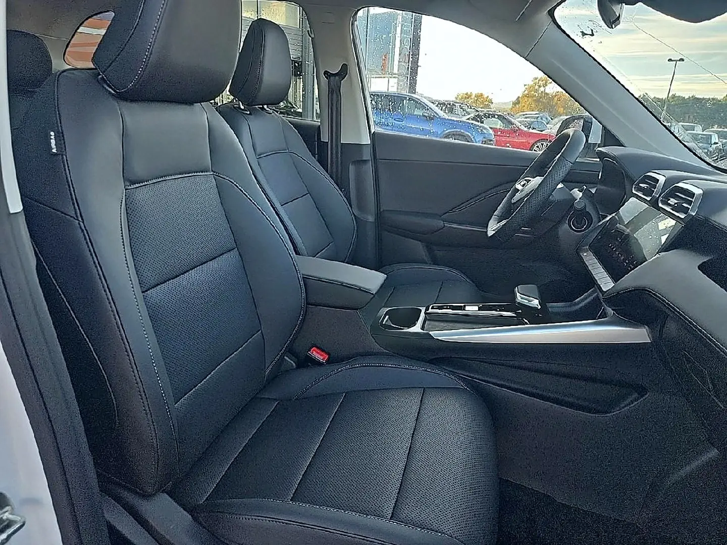 Vue intérieure côté conducteur du MG Motor ZS 1.5 hybrid 197 luxury avec sièges noir similicuir et console centrale moderne.
