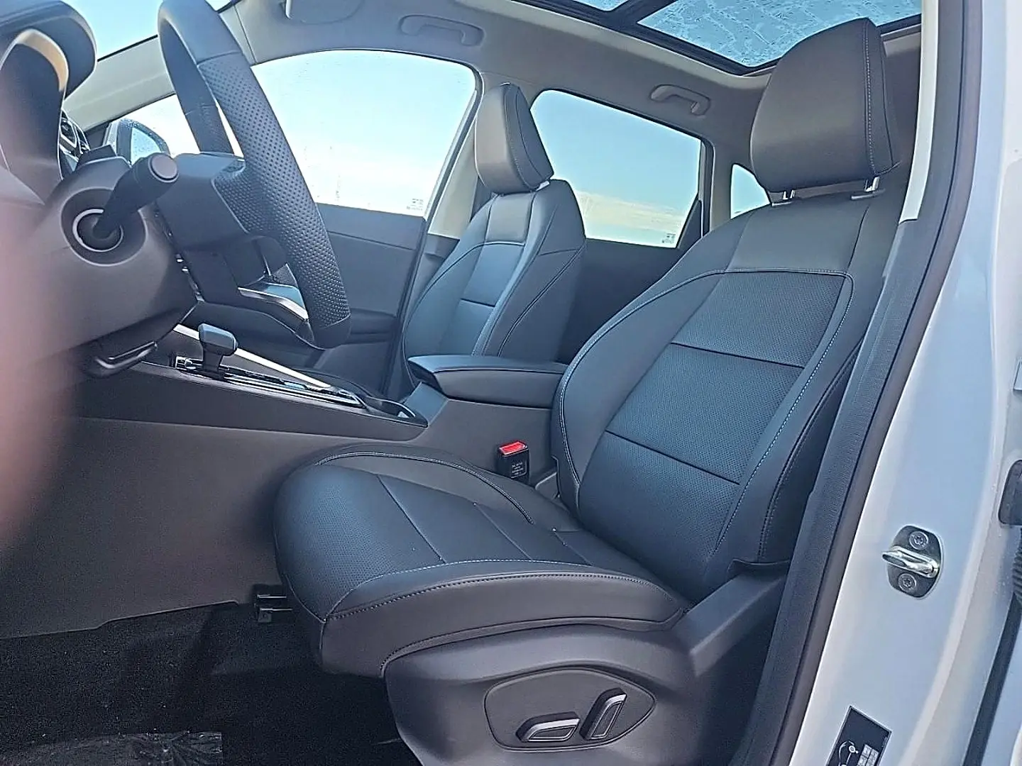 Vue intérieure côté conducteur du MG ZS blanc 2026, sièges en similicuir noir avec toit panoramique en verre visible.