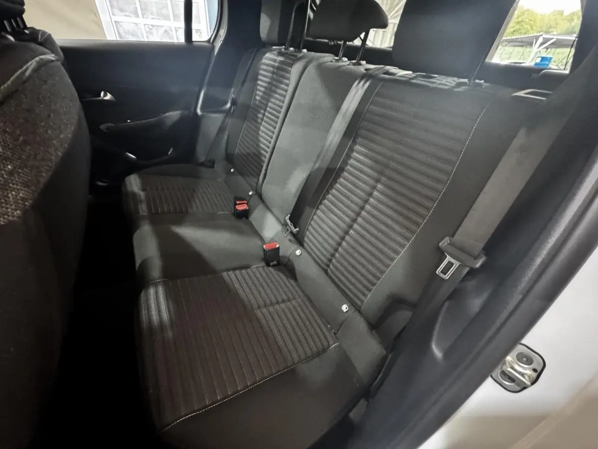 Vue intérieure arrière droite de la banquette noire de la Peugeot 208 PureTech 75 S&S Active blanche 2024.