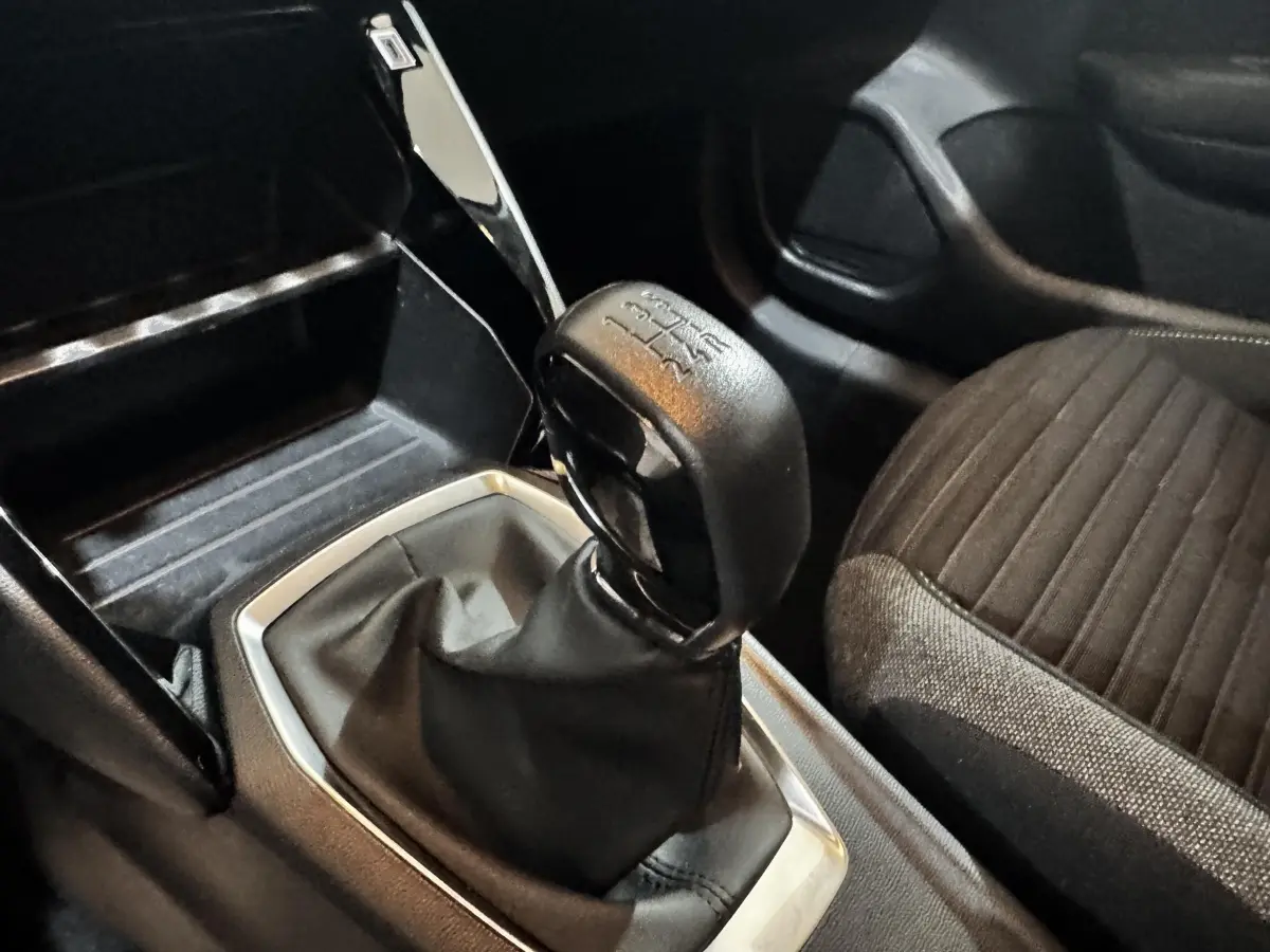 Gros plan sur le levier de vitesse manuel et la console centrale noire à l'intérieur d'une Peugeot 208 blanche.