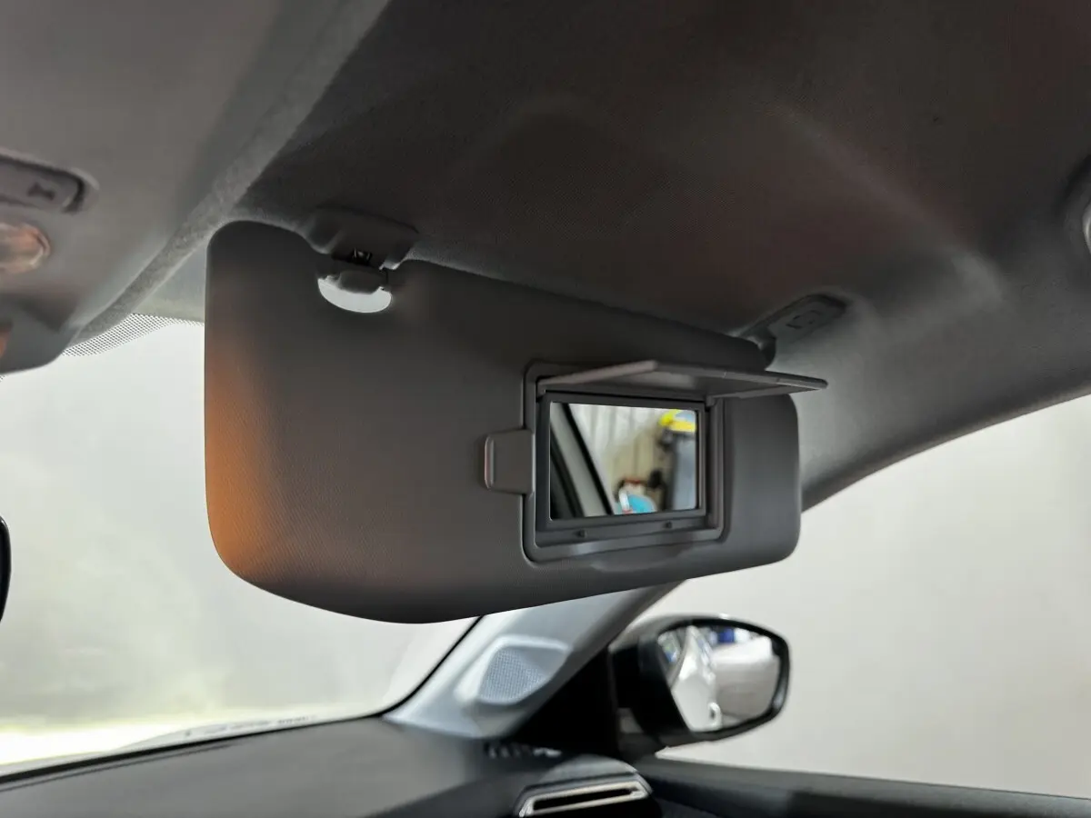 Miroir de courtoisie ouvert sur pare-soleil côté conducteur dans l'habitacle d'une Peugeot 208 blanche.