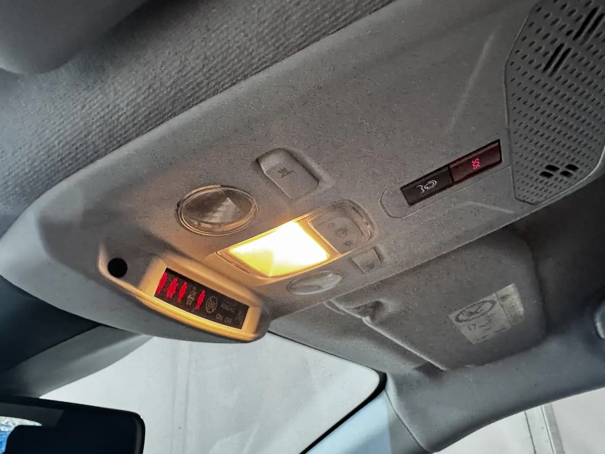 Plafonnier intérieur allumé de la Peugeot 208 blanche PureTech 75 S&S Active, vue en contre-plongée vers l’avant.