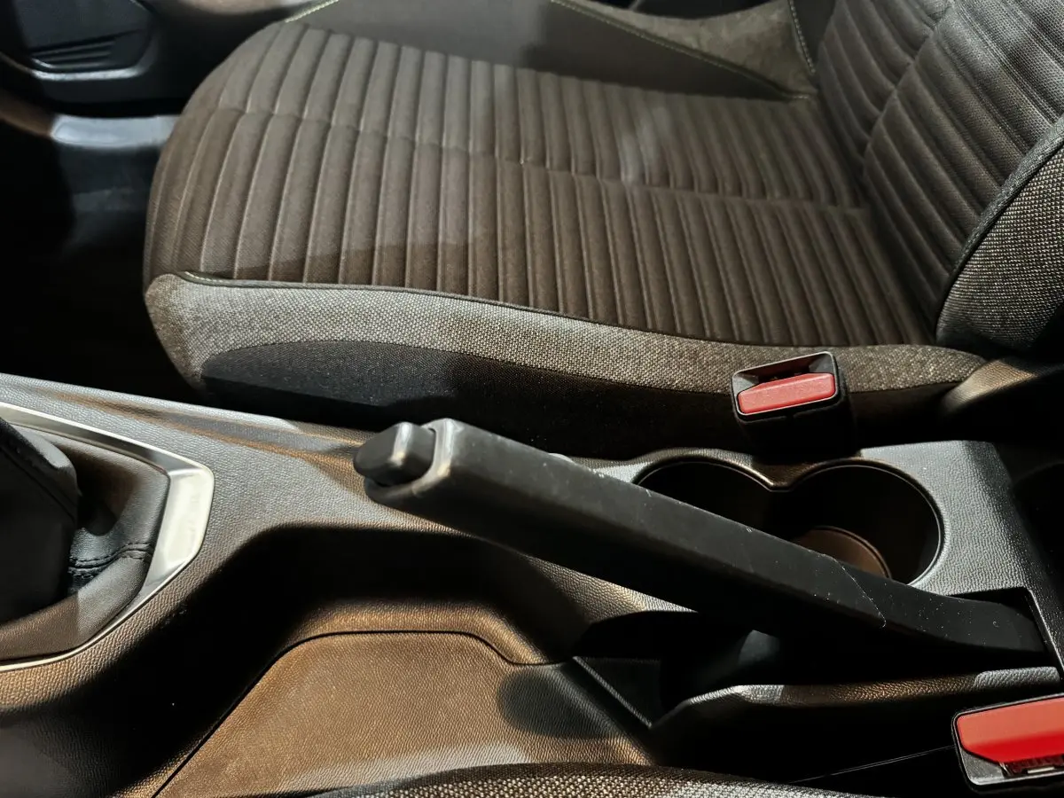 Gros plan sur la console centrale et le frein à main de la Peugeot 208 PureTech 75 S&S Active avec siège tissu marron.