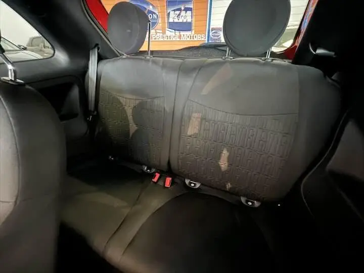 Vue intérieure arrière des sièges noirs de la Fiat 500 rouge, avec appuie-têtes ronds et tissu texturé.