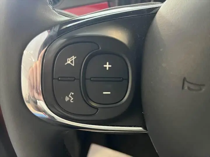 Gros plan sur les commandes de volume et de son du volant d'une FIAT 500 rouge 2023, finition Pack Confort et Style.