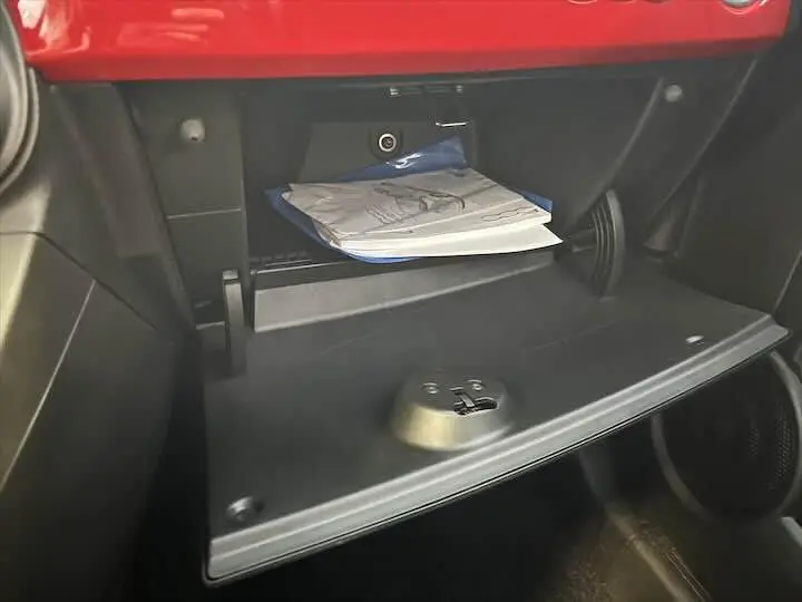 Gant de boîte à gants ouvert avec notice visible à l'intérieur d'une Fiat 500 rouge 2023.