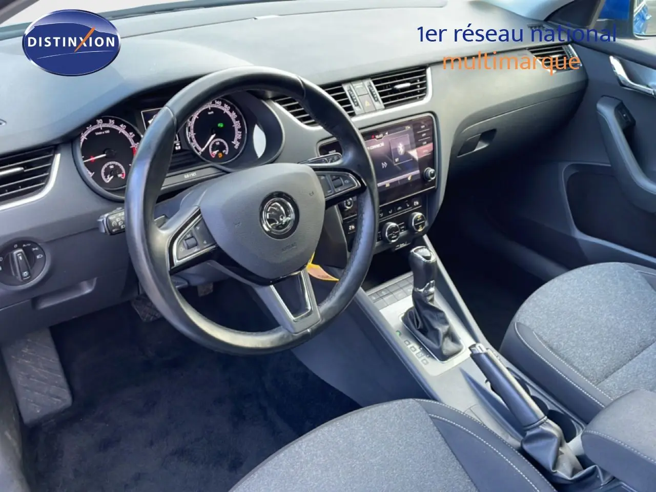 Vue intérieure côté conducteur de la Skoda Octavia Combi 2019, tableau de bord et volant en cuir avec console centrale et boîte auto.