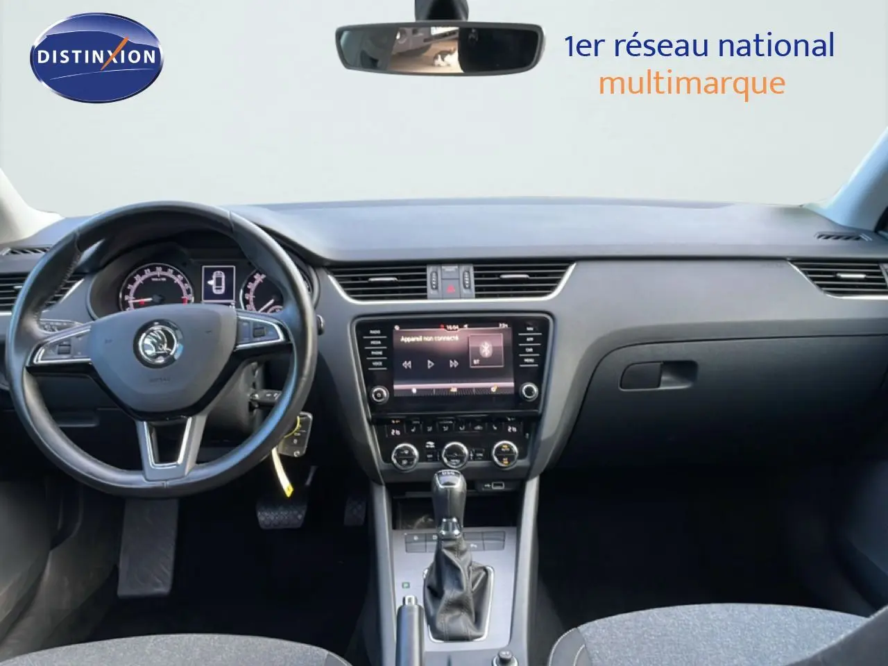 Vue frontale de l’intérieur d’une Skoda Octavia Combi 2019, tableau de bord et volant noir avec écran central tactile.