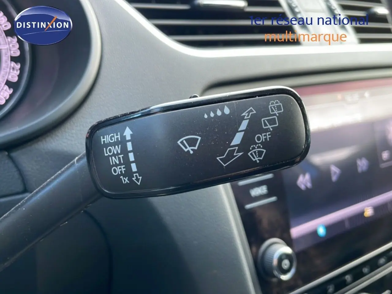 Gros plan sur la commande des essuie-glaces à gauche du volant dans l’habitacle gris d’une Skoda Octavia Combi bleu racing metal.