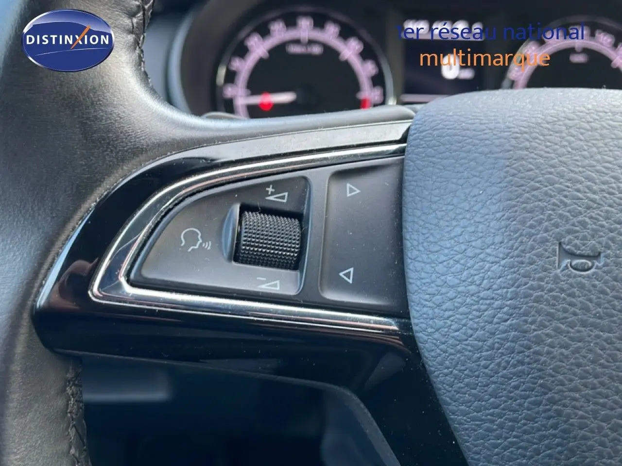 Gros plan sur les commandes gauche du volant en cuir noir de la Skoda Octavia Combi 2019, tableau de bord flou en arrière-plan.