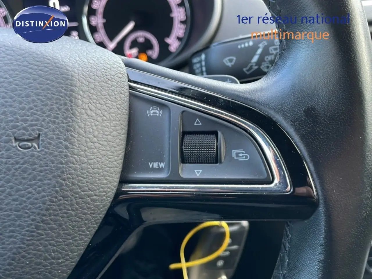 Gros plan sur le volant noir de la Skoda Octavia Combi 2019, montrant les commandes multifonctions et le tableau de bord flou.