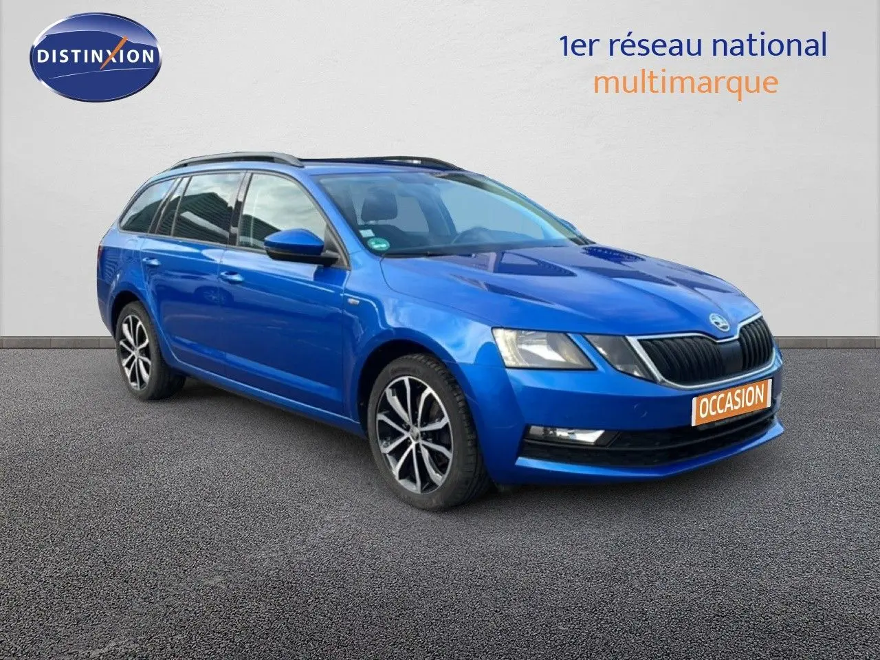 Vue 3/4 avant gauche d'une Skoda Octavia Combi bleu racing metal avec jantes alliage et toit ouvrant visible.