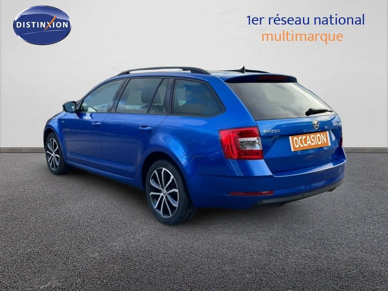 Vue 3/4 arrière gauche d’une Skoda Octavia Combi bleu racing metal avec jantes alliage et toit ouvrant.