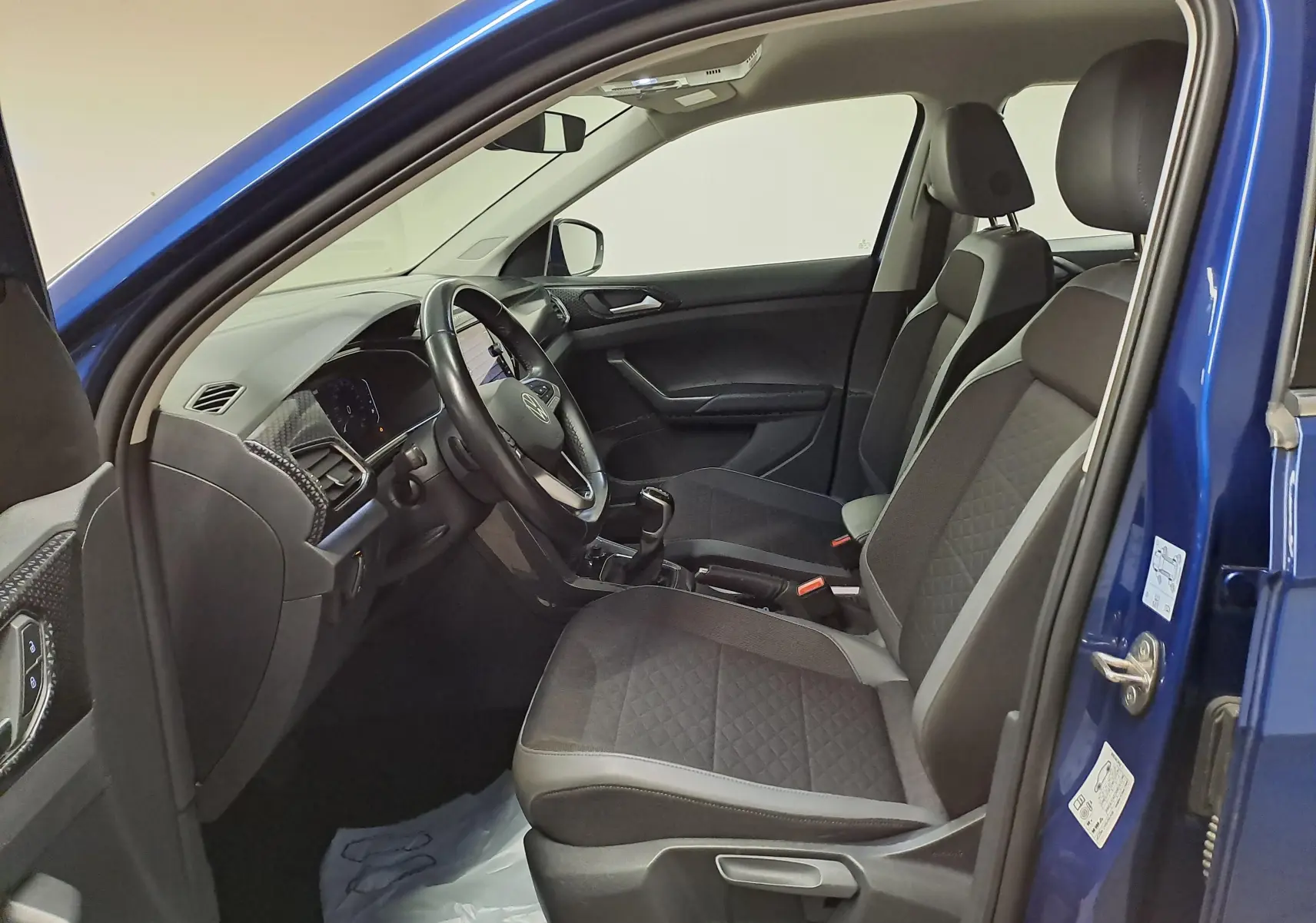 Vue intérieure côté conducteur du Volkswagen T-Cross Bleu Récif 2022, montrant sièges et tableau de bord moderne.